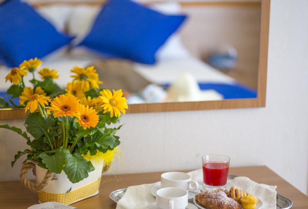 Colazione con fiori, croissant e succo su un tavolo.