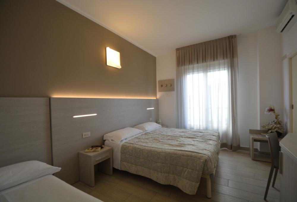 Modern room with a double and single bed, soft lighting.