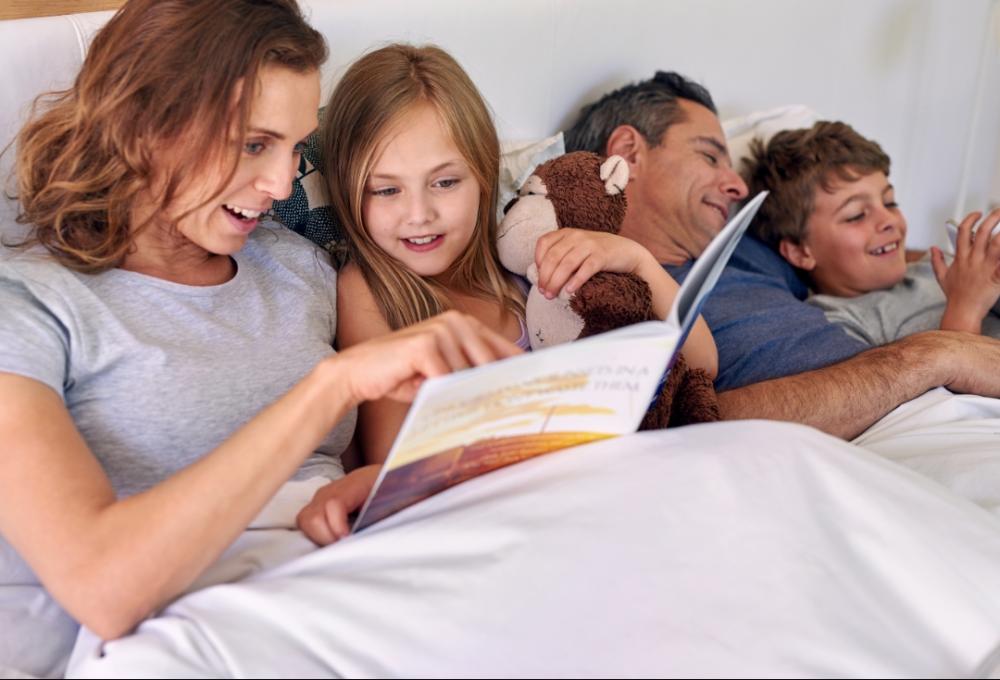 Family reading together in bed, smiling.
