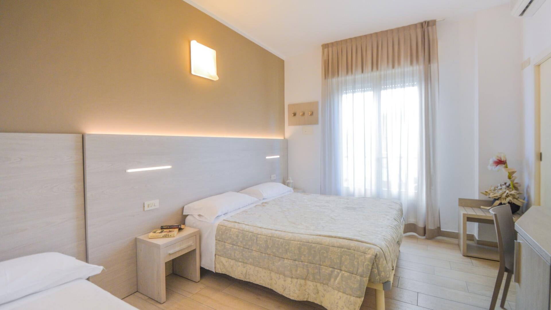Helles Zimmer mit Doppelbett, modernen Möbeln und großem Fenster.