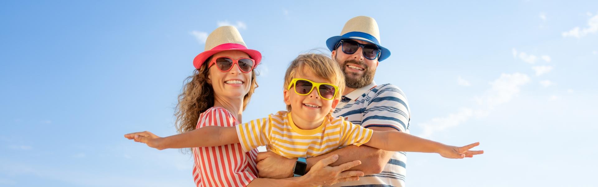 Happy family at the beach with child pretending to be an airplane.