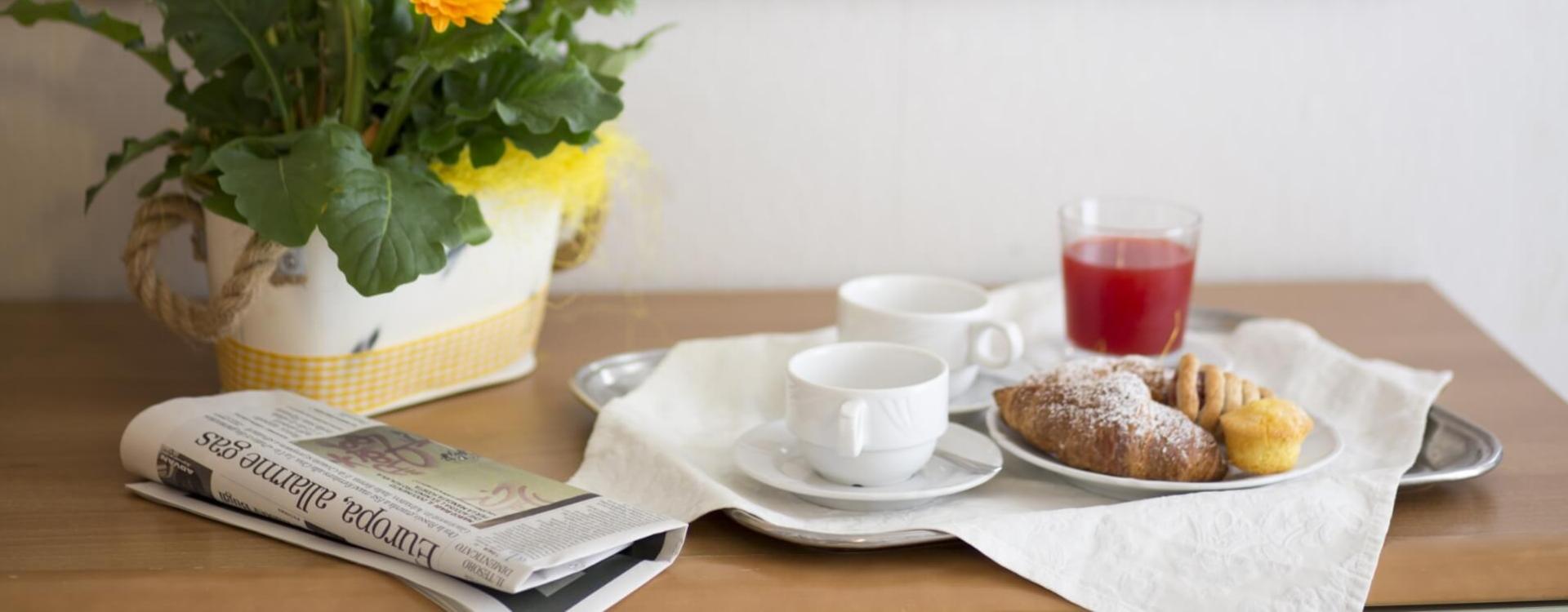 Breakfast with yellow flowers, newspaper, and red drink on a tray.