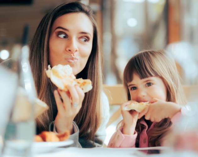 Zwei Personen essen Pizza in einem Restaurant.